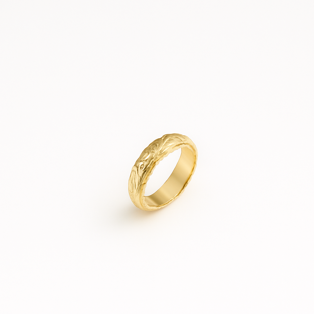 Gold wedding band with intricate leaf pattern design on a white background. Elegant and timeless jewelry piece for engagements or anniversaries.