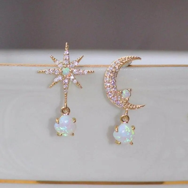 Gold star and moon earrings with opal gemstones, featuring sparkling crystals. Unique celestial jewelry design for fashion and style enthusiasts.