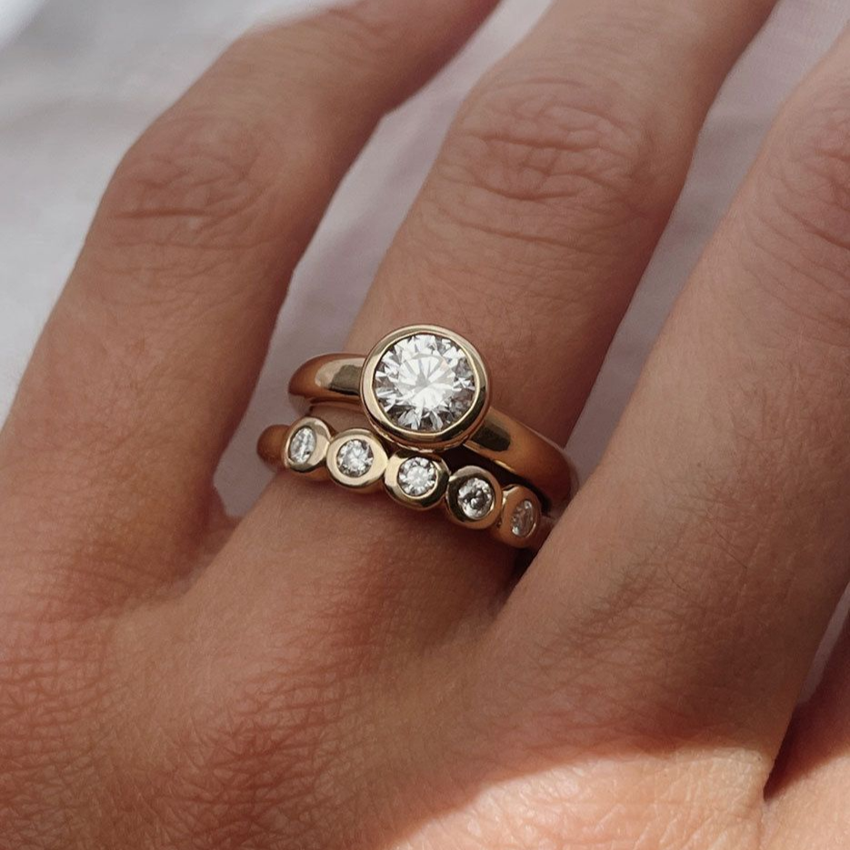 Rose gold ring with diamond stones on a hand against a neutral background