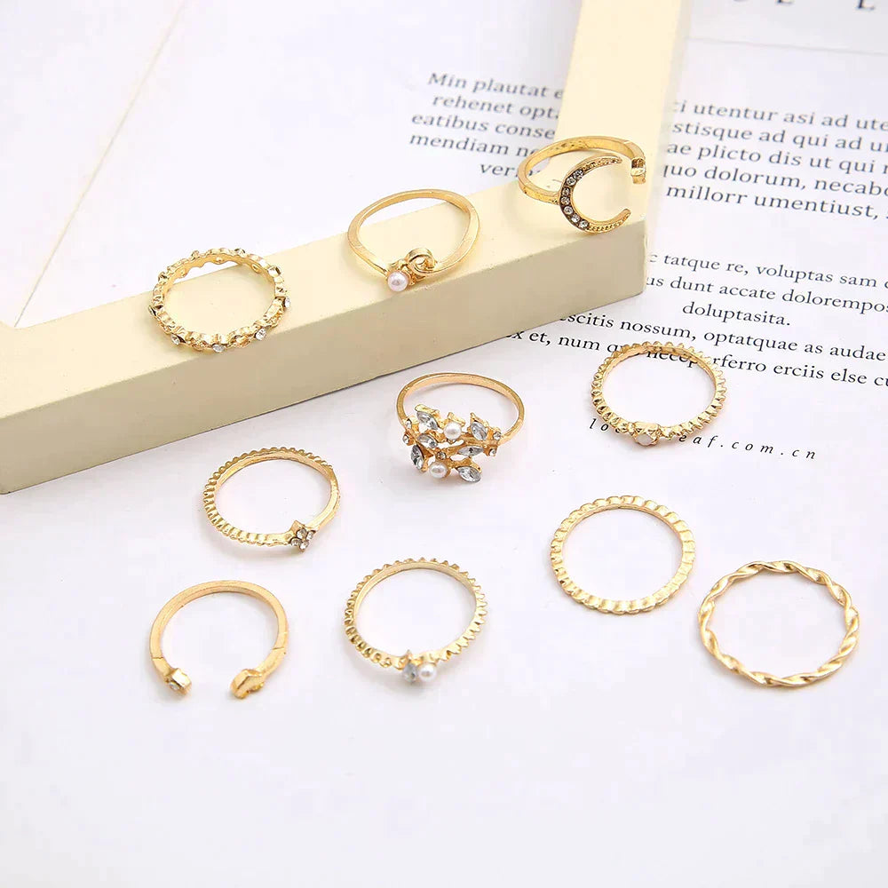 Gold rings set with pearls and crystals on a white background, featuring various designs including twisted and braided styles, perfect for fashion accessories.