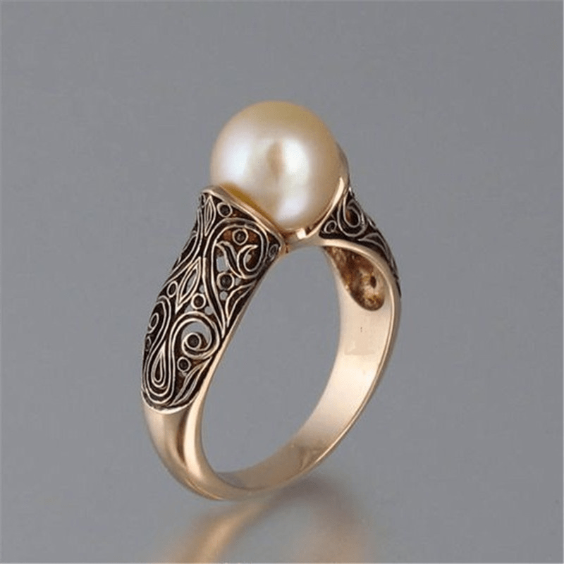 Elegant gold ring with intricate filigree design, featuring a lustrous pearl centerpiece. Perfect for luxury jewelry enthusiasts and collectors.