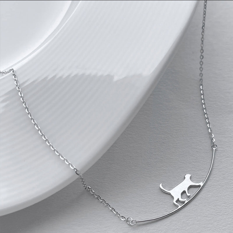 Silver cat necklace on a delicate chain, elegantly displayed on a white ceramic plate. Perfect for cat lovers, minimalist jewelry, fashion accessory.