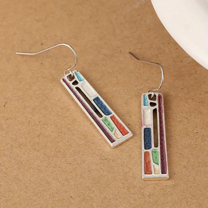 Colorful geometric dangle earrings with rectangular design, featuring multicolored inlays on a brown background. Fashion jewelry accessory.
