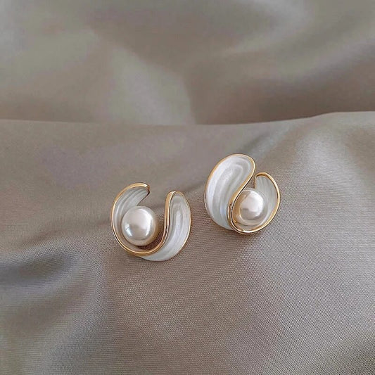 Elegant pearl earrings with gold accents on a silky gray fabric background, showcasing luxury jewelry design and fashion accessories.