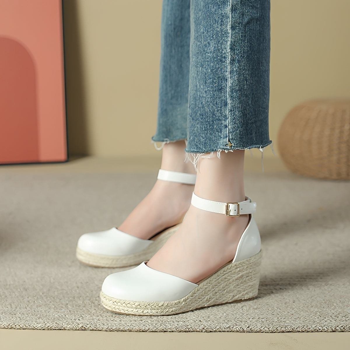 White wedge sandals with espadrille sole worn by a person in denim jeans.