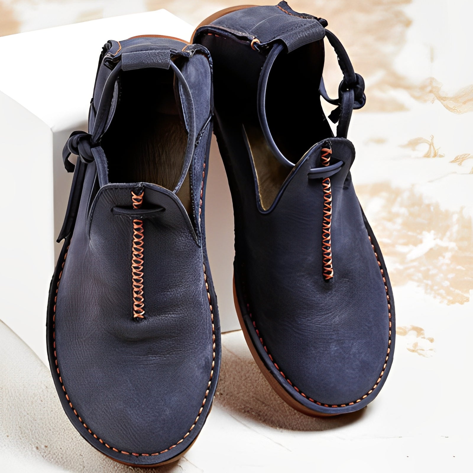 Pair of blue leather shoes with brown stitching on a light background