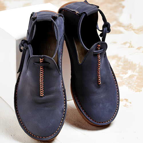 Pair of blue leather shoes with brown stitching on a light background