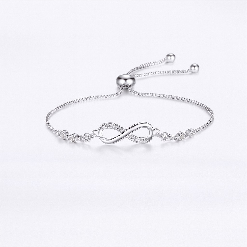 Silver infinity bracelet with adjustable chain and cubic zirconia accents on a white background. Elegant jewelry for women, perfect gift idea.