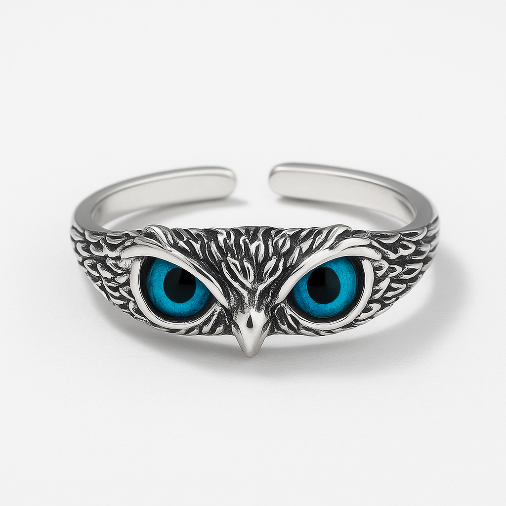 Silver owl bracelet with intricate feather detailing and striking blue eyes, showcasing unique wildlife-inspired jewelry design on a white background.