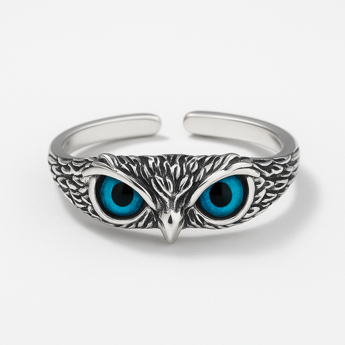 Silver owl bracelet with intricate feather detailing and striking blue eyes, showcasing unique wildlife-inspired jewelry design on a white background.