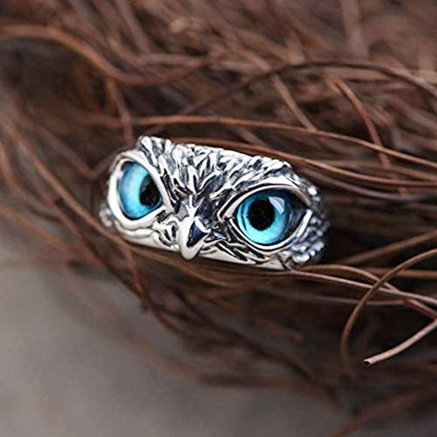Silver owl ring with striking blue eyes nestled in twigs, showcasing intricate design and craftsmanship. Unique jewelry piece, nature-inspired accessory.