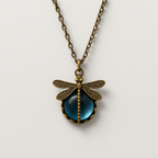 Antique bronze dragonfly pendant necklace with intricate detailing and a blue gemstone center, on a matching chain. Vintage jewelry accessory.
