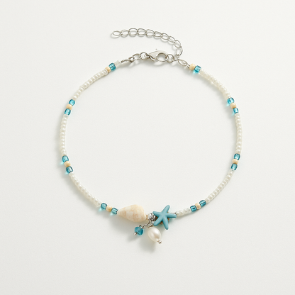 Beach-themed anklet with turquoise beads, seashell, starfish charm, and pearl on a silver chain. Coastal jewelry, summer accessory, boho style.