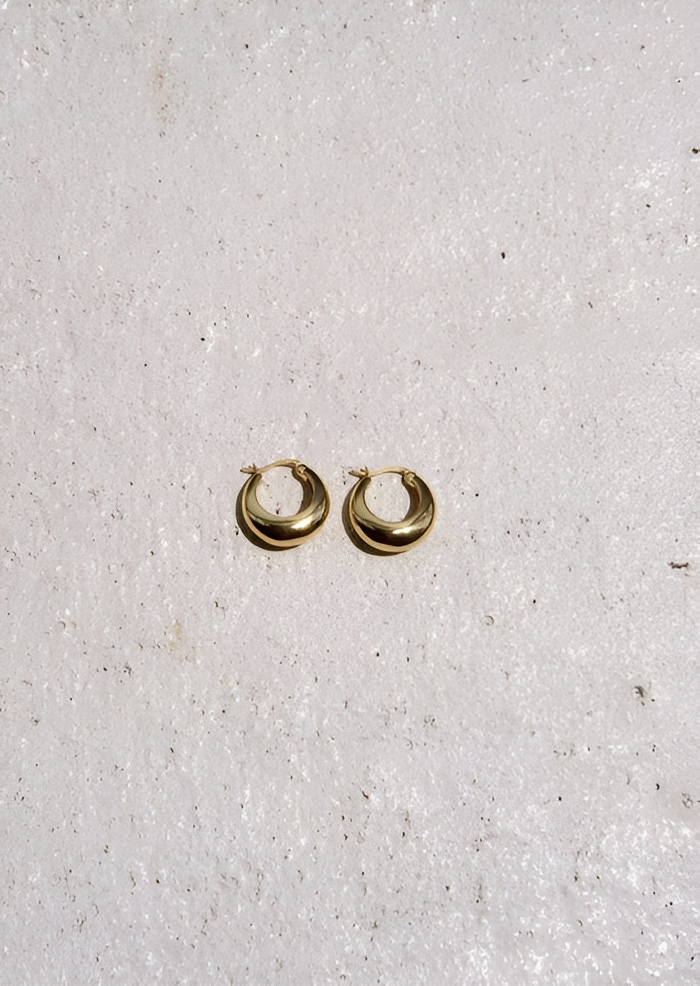Gold hoop earrings on a light gray background
