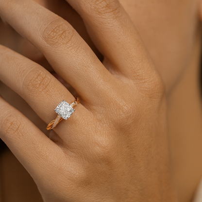 Rose gold ring with a diamond on a hand against a neutral background
