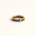 Gold and black ring with diamond accents on a beige background