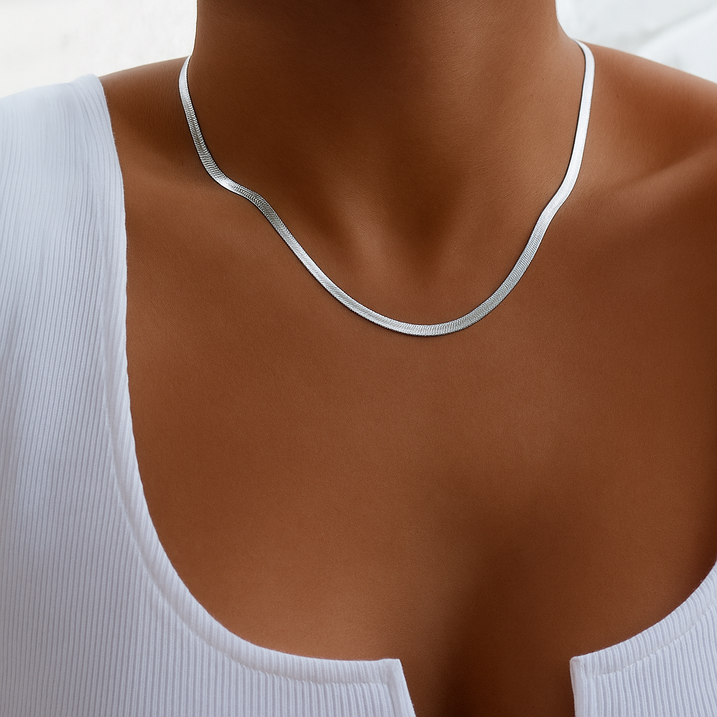Elegant silver snake chain necklace on woman wearing a white ribbed tank top, showcasing minimalist jewelry fashion and style.