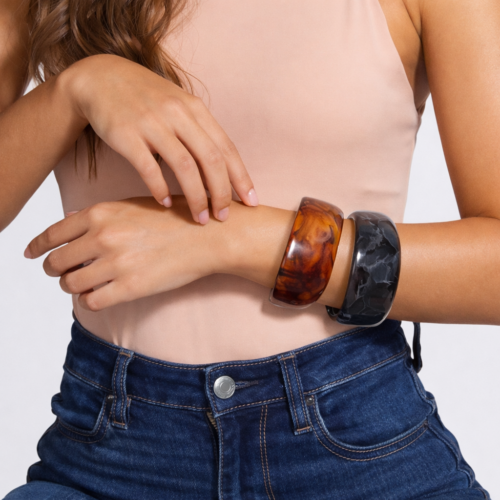 Person wearing tortoiseshell bangles on a plain background