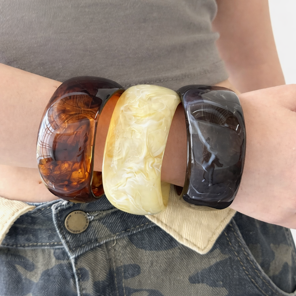 Three marbled resin bracelets on a wrist with a neutral background