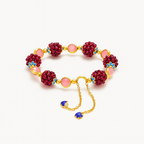 Gold chain bracelet with red beaded clusters, pink stones, and blue floral accents, featuring adjustable chain and blue charms. Elegant jewelry accessory.