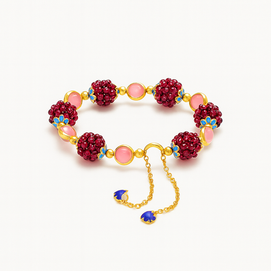 Gold chain bracelet with red beaded clusters, pink stones, and blue floral accents, featuring adjustable chain and blue charms. Elegant jewelry accessory.