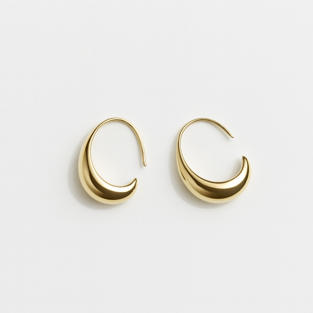 Gold crescent hoop earrings on white background, minimalist jewelry design, elegant fashion accessory, modern gold earrings for women.