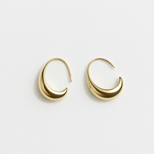 Gold crescent hoop earrings on white background, minimalist jewelry design, elegant fashion accessory, modern gold earrings for women.