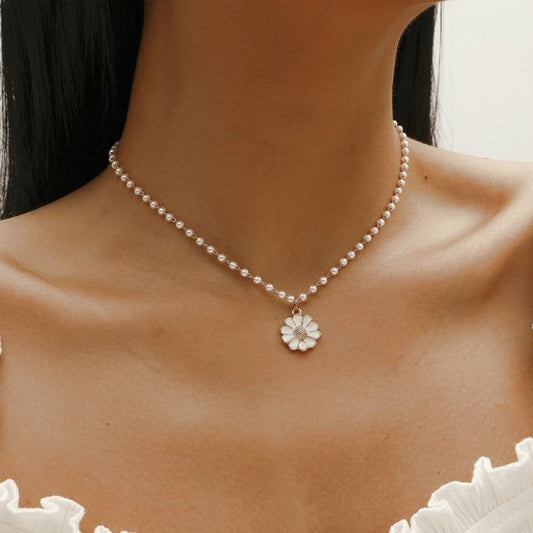 Woman wearing a pearl necklace with a floral pendant, showcasing elegant jewelry fashion. Perfect for bridal accessories and luxury style inspiration.