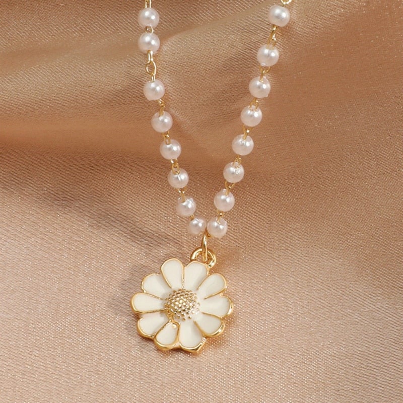 Gold daisy pendant necklace with pearl chain on satin background, elegant floral jewelry, fashion accessory, delicate design, gift for her.