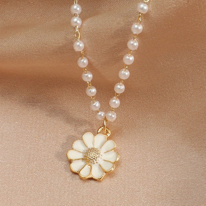 Gold daisy pendant necklace with pearl chain on satin background, elegant floral jewelry, fashion accessory, delicate design, gift for her.