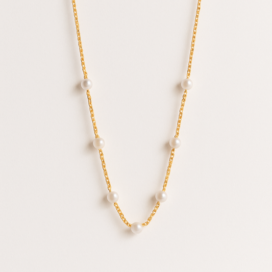 Gold chain necklace with evenly spaced white pearls, minimalist jewelry design, elegant fashion accessory, perfect for formal occasions.