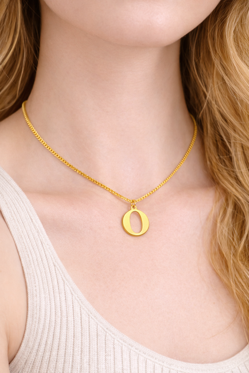 Gold necklace with a 'O' pendant worn by a person