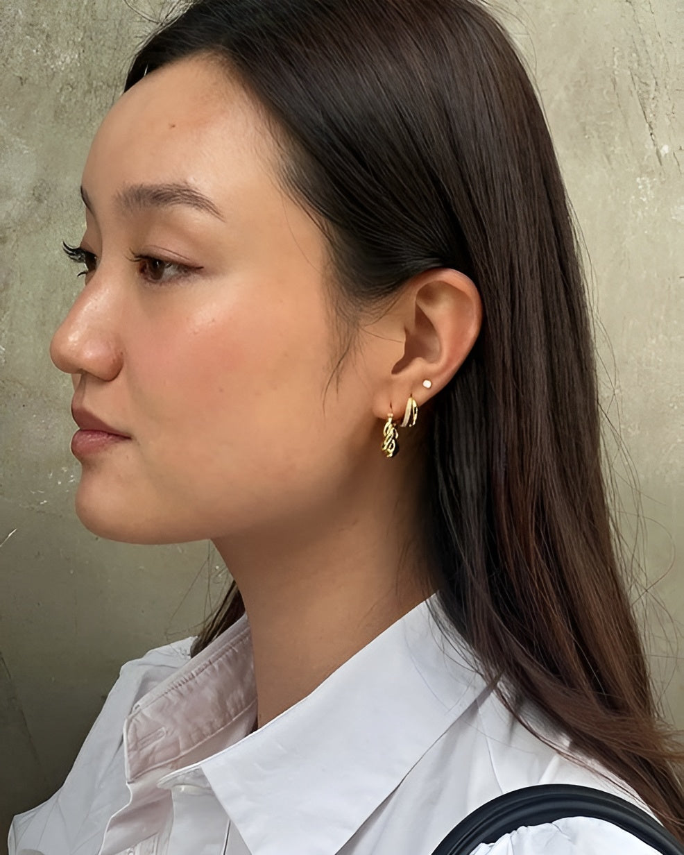 Woman wearing gold hoop earrings with a neutral background