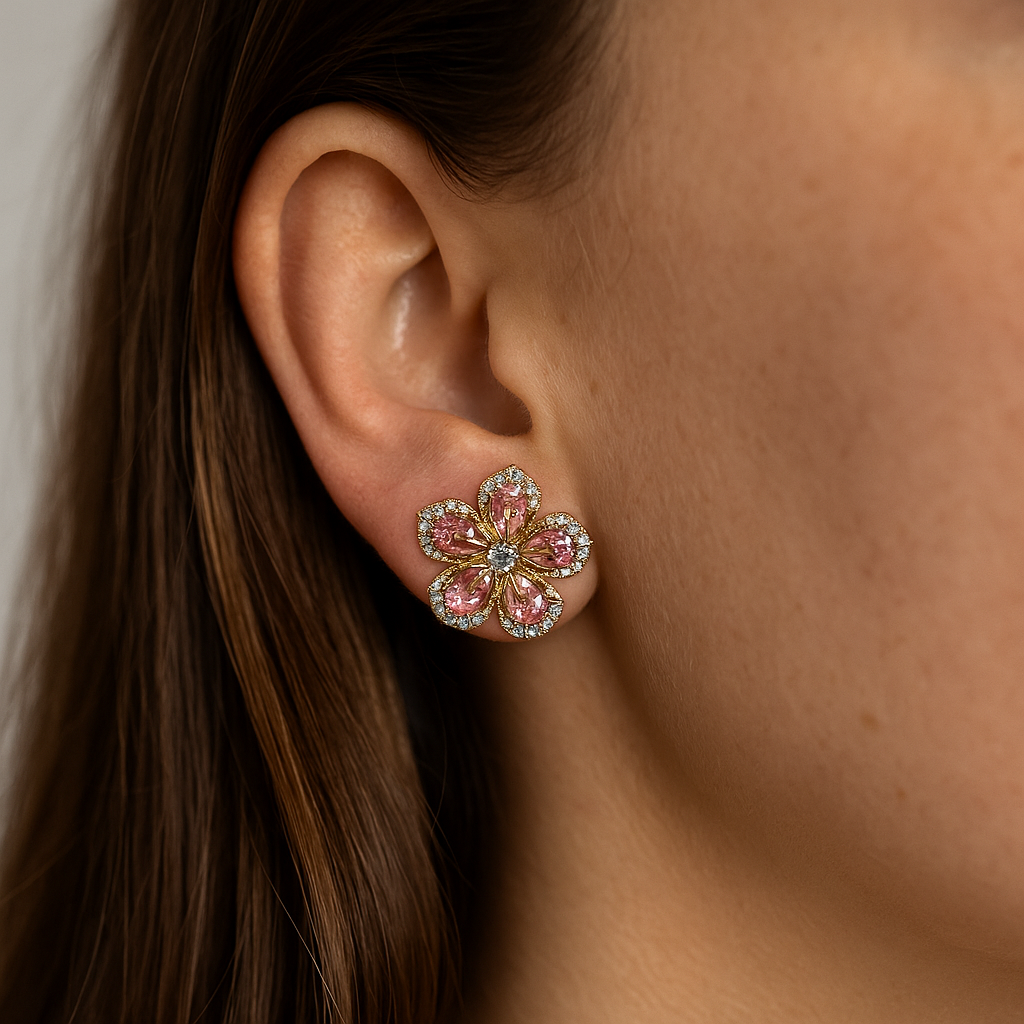 Close-up of an ear wearing a floral earring with pink gemstones.