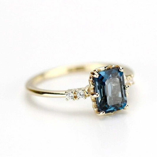 Elegant gold ring featuring a rectangular blue sapphire centerpiece with diamond accents, perfect for engagement or special occasions.