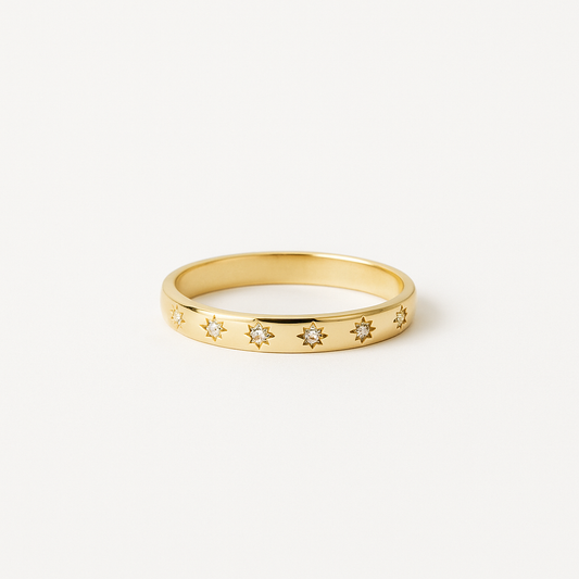 Gold ring with star-shaped gemstones on a white background