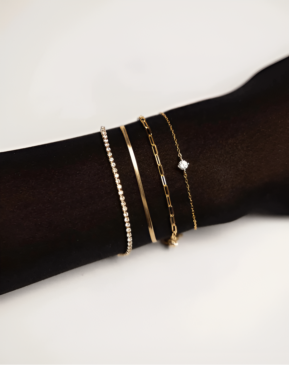 Gold bracelets on a wrist against a white background