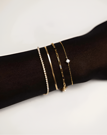 Gold bracelets on a wrist against a white background