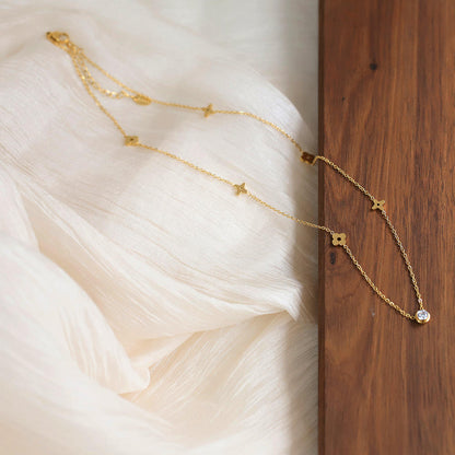 Gold necklace with star-shaped pendants on a soft fabric background