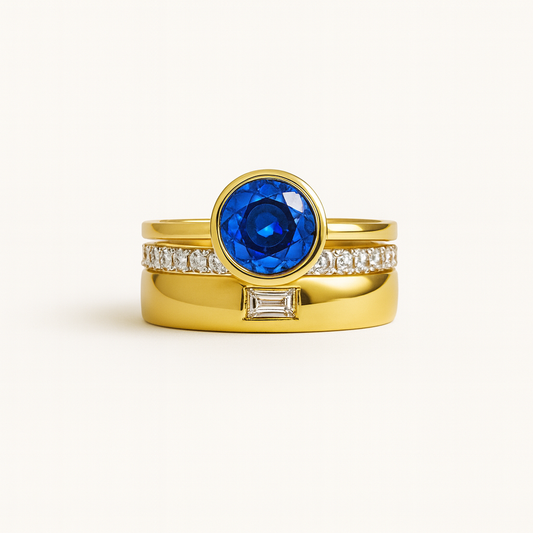 Gold ring with a blue gemstone and diamond accents on a white background