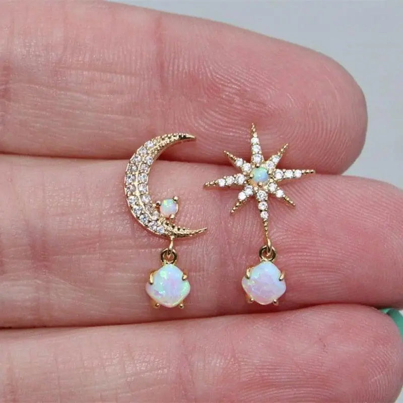Gold moon and star earrings with opal and diamond accents, held in hand. Celestial jewelry, opal earrings, moon and star design, sparkling gemstones.