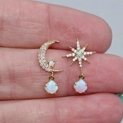 Gold moon and star earrings with opal and diamond accents, held in hand. Celestial jewelry, opal earrings, moon and star design, sparkling gemstones.