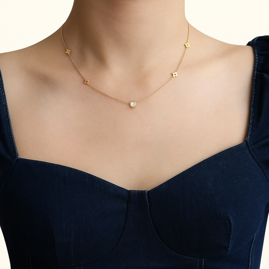 Woman wearing a delicate gold necklace with star-shaped charms and a central diamond pendant, paired with a dark blue off-shoulder dress.