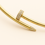 Gold nail bracelet with diamond accents on a beige background, luxury jewelry, elegant design, high-end fashion accessory, sparkling gemstones.