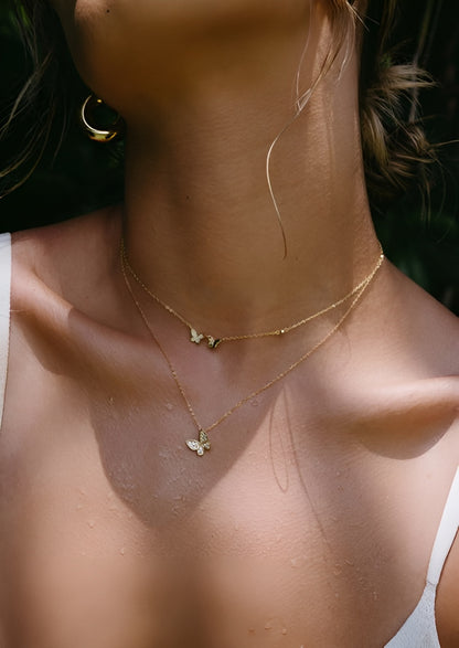 Close-up of a person wearing a delicate gold necklace with a small pendant.