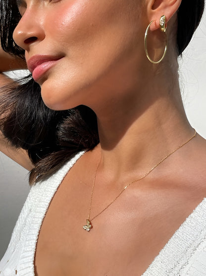 Close-up of a woman wearing gold hoop earrings and a delicate necklace with a pendant.