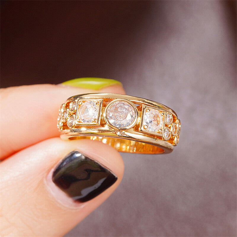Gold ring with diamonds held by a hand against a blurred background