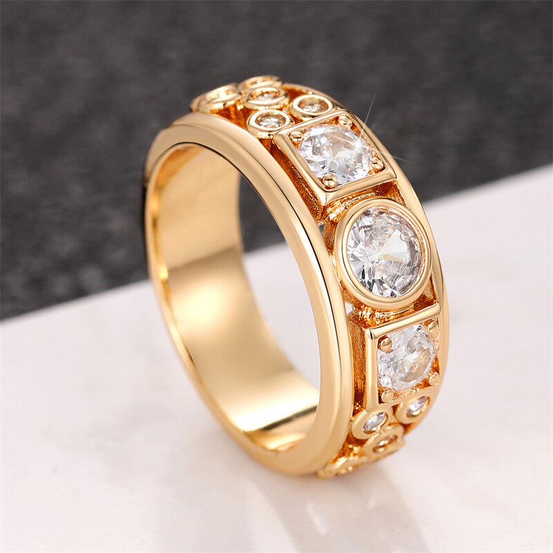 Gold ring with embedded diamonds on a reflective surface