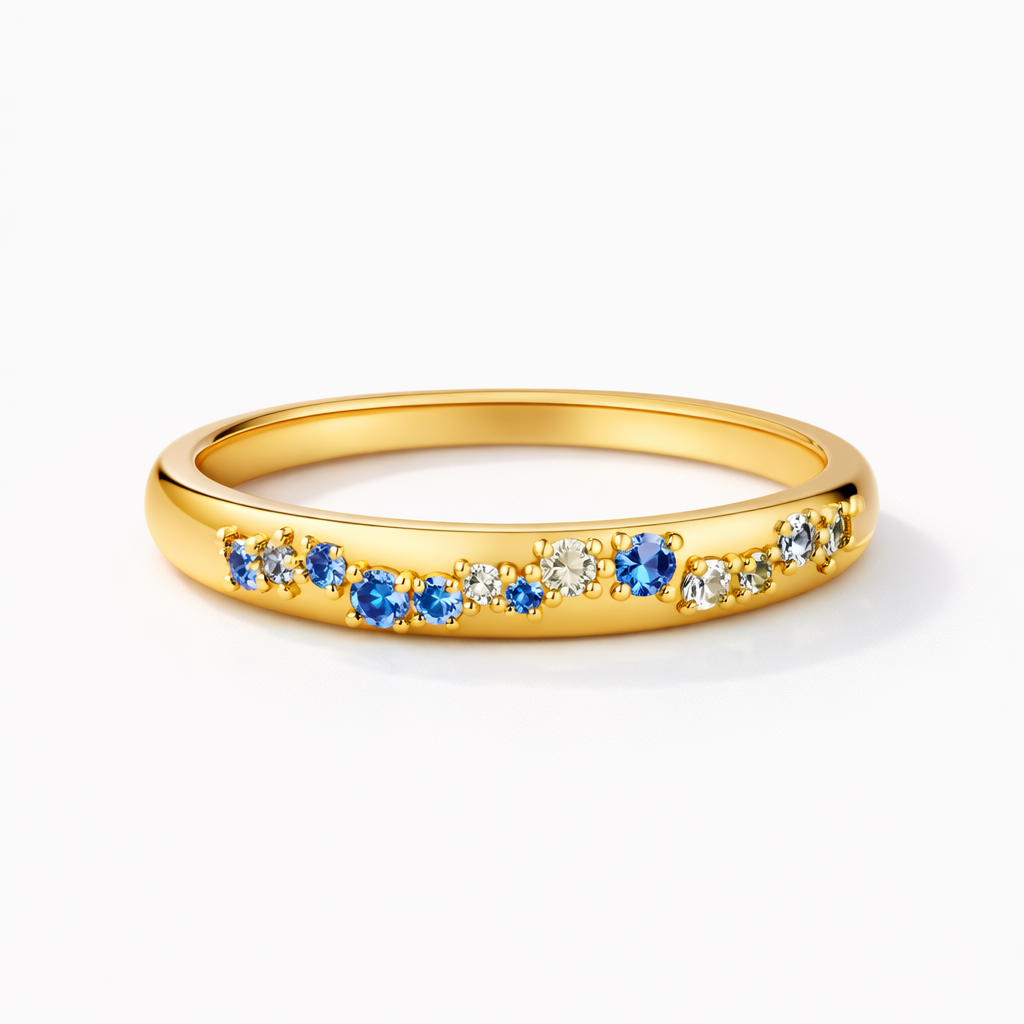 Gold ring with blue and clear gemstones on a white background