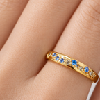 Gold ring with blue and clear gemstones on a person's finger